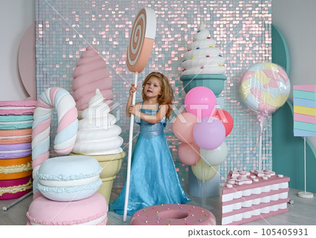 Little girl in a blue dress with a toy candy lollipop Little girl in a blue dress with a toy candy lollipop 105405931