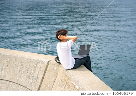 一個男人突然在旅行目的地的海邊開始遠程工作 一個男人突然在旅行目的地的海邊開始遠程工作 105406179