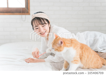 Asian female owner playing with her cat using cat teaser Asian female owner playing with her cat using cat teaser 105406709