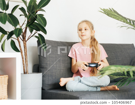 Girl playing video game at home Girl playing video game at home 105406967