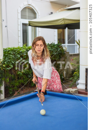 Young blond woman playing billiards in the backyard 105407325