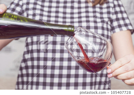 Woman pouring herself glass of wine. Woman drinking alcoholic beverages alone 105407728