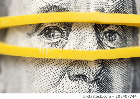 Portrait of Benjamin Franklin on a hundred dollar bill with eyes in rubber band Portrait of Benjamin Franklin on a hundred dollar bill with eyes in rubber band 105407744