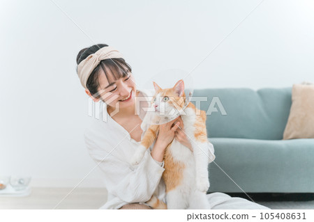 A cat with an Elizabethan collar at home and a woman who owns it 105408631
