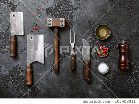 Kitchen meat utensils set on dark plate background. Meat cleaver,fork,knife 105409011