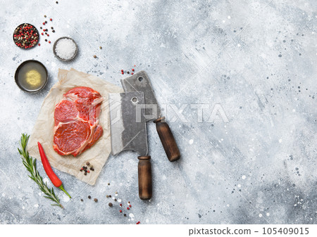 Fillet of raw beef rib eye steak on with meat cleaver,salt and pepper on light 105409015