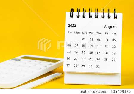 The August 2023 Monthly desk calendar for 2023 year and calculator with pen on yellow background. 105409372