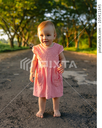 Beautiful child girl in outdoor with sunset. Cute baby in pink dress in park. Beautiful child girl in outdoor with sunset. Cute baby in pink dress in park. 105411845