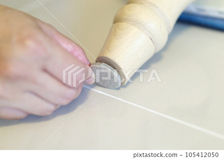 Woman sticking floor care pad at sofa leg Woman sticking floor care pad at sofa leg 105412050