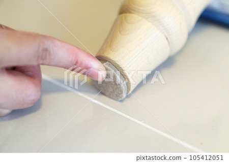 Woman sticking floor care pad at sofa leg Woman sticking floor care pad at sofa leg 105412051