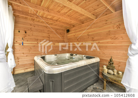 a bathroom with a hot tub in the middle and wood paneled walls on the wall behind it, there is a towel hanging 105412608