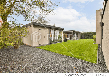 a backyard area with a shed and green grass in the yard is surrounded by trees, shrubs and bushes on both sides 105412612