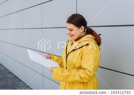 Young woman in yellow uniform holding package. Delivery service holding to sent a white package letter, for mockup. Concept of fast delivery Young woman in yellow uniform holding package. Delivery service holding to sent a white package letter, for mockup. Concept of fast delivery 105412791