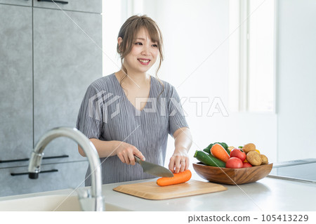 Asian woman, pregnant woman, pre-mama who cooks and cuts vegetables in the kitchen Asian woman, pregnant woman, pre-mama who cooks and cuts vegetables in the kitchen 105413229