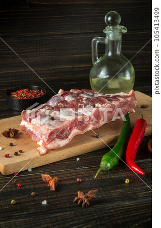 Raw beef short ribs on a cutting board with spices and seasonings. Preparing to cook delicious food for the hotel. Raw beef short ribs on a cutting board with spices and seasonings. Preparing to cook delicious food for the hotel. 105413499