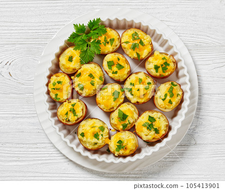 baked stuffed red potato on white baking dish 105413901