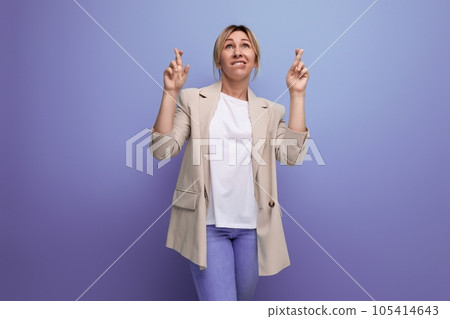 portrait of hopeful business woman in jacket with fingers crossed in studio with copy space portrait of hopeful business woman in jacket with fingers crossed in studio with copy space 105414643