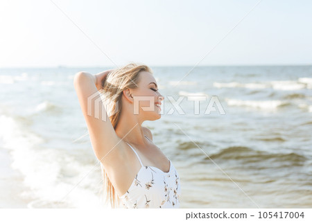 Happy blonde woman in free happiness bliss on ocean beach standing straight and posing 105417004