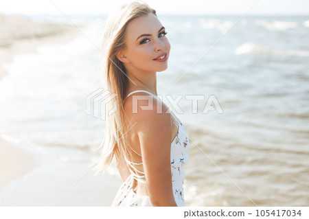 Happy blonde woman in free happiness bliss on ocean beach standing straight and posing Happy blonde woman in free happiness bliss on ocean beach standing straight and posing 105417034