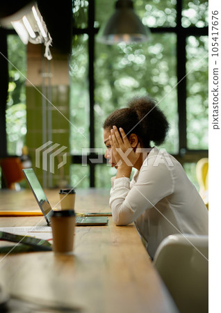 Shocked worried business woman looking at laptop sitting in office Shocked worried business woman looking at laptop sitting in office 105417676