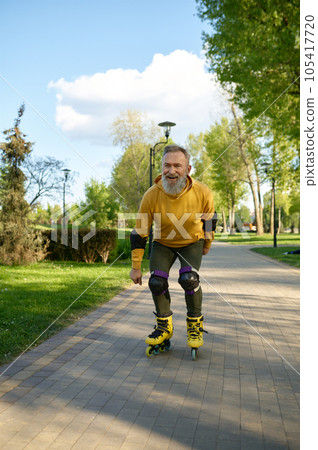 Happy playful mature man rollerskating on pathway in city park Happy playful mature man rollerskating on pathway in city park 105417720