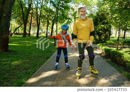 Happy senior man and little boy rollerskating in urban park 105417733