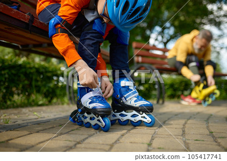 Selective focus of grandson and grandfather putting on roller skates Selective focus of grandson and grandfather putting on roller skates 105417741