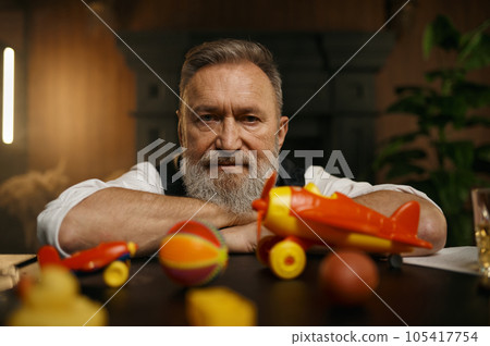 Portrait of thoughtful senior businessman with toys while rest 105417754