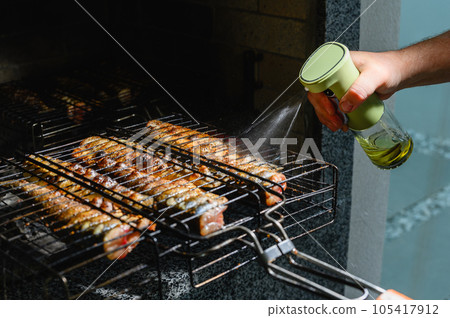 Male hand watered with olive oil, spices fish, baked on a grill. Male hand watered with olive oil, spices fish, baked on a grill. 105417912