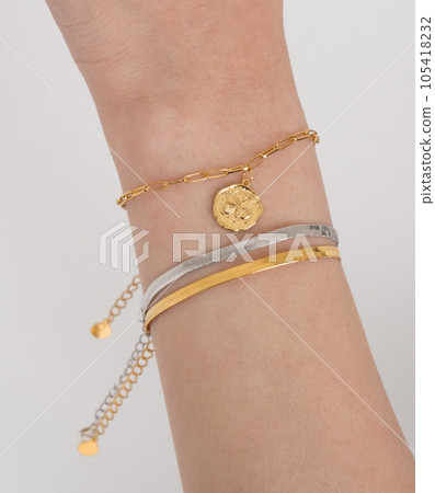 Woman wrist wearing golden butterfly and snake chain bracelets set against a white background. Beautiful valentine's gift. Woman wrist wearing golden butterfly and snake chain bracelets set against a white background. Beautiful valentine's gift. 105418232
