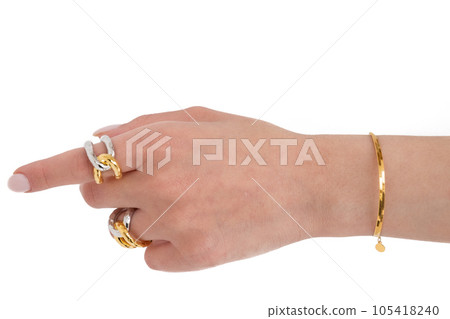 Woman hand wearing golden Snake Chain bracelet and Interlocked Golden and Silver Rings set against a white background. Beautiful valentine's gift. Woman hand wearing golden Snake Chain bracelet and Interlocked Golden and Silver Rings set against a white background. Beautiful valentine's gift. 105418240