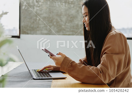 Young asian woman using smartphone and laptop at home. 105420242