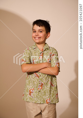 Vertical portrait of a handsome teen boy in a summer patterned shirt, crossing hands, smiling broadly looking at camera Vertical portrait of a handsome teen boy in a summer patterned shirt, crossing hands, smiling broadly looking at camera 105421097