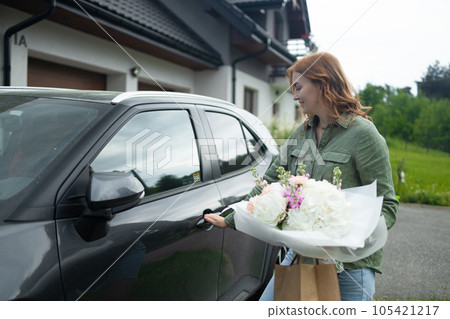 Female happy lady with bouquet of flowers near car outdoors. Sexy carefree woman posing on the street background Female happy lady with bouquet of flowers near car outdoors. Sexy carefree woman posing on the street background 105421217