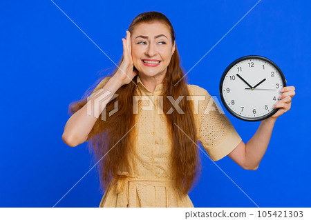 Adult woman with anxiety checking time on clock, running late to work, being in delay, deadline 105421303