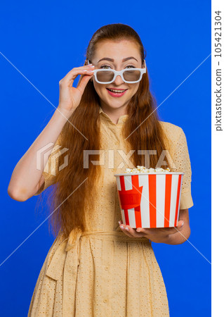 Adult woman in 3D glasses eating popcorn watching TV serial, sport game, film, online movie content Adult woman in 3D glasses eating popcorn watching TV serial, sport game, film, online movie content 105421304