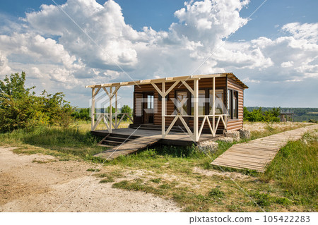 Small modern house in a clear field with wooden boardwalk 105422283