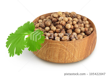 Dried coriander seeds in the wooden bowl with fresh green leaf isolated on white background 105422847
