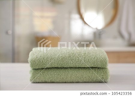 Stack of clean towels on white wooden table in bathroom 105423356