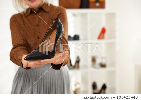 Female business owner showing shoe in boutique, closeup. Space for text Female business owner showing shoe in boutique, closeup. Space for text 105423448