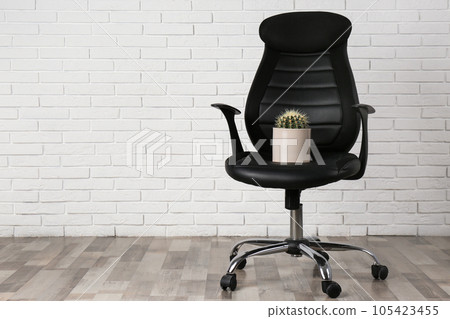 Office chair with cactus near white brick wall, space for text. Hemorrhoids concept 105423455