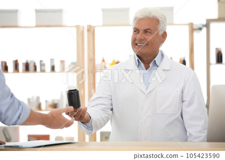 Pharmacist giving medicine to customer in drugstore Pharmacist giving medicine to customer in drugstore 105423590