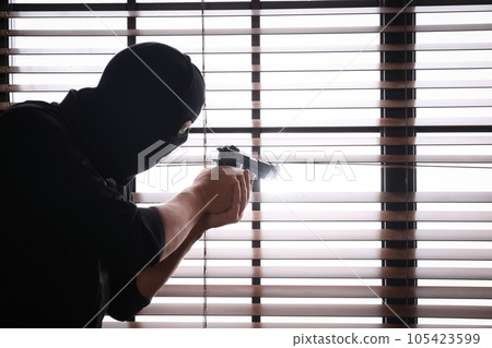 Man in mask aiming through window blinds indoors. Space for text 105423599