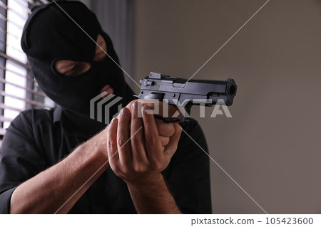Man in mask holding gun indoors, focus on hands 105423600