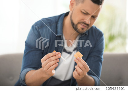 Emotional man with nicotine patch and cigarette at home, focus on hands Emotional man with nicotine patch and cigarette at home, focus on hands 105423601