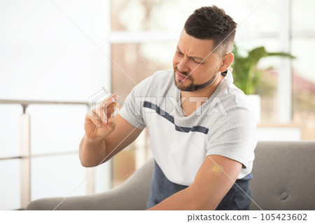 Emotional man with nicotine patch and cigarette at home Emotional man with nicotine patch and cigarette at home 105423602