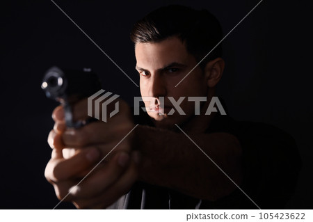 Professional killer with gun on black background Professional killer with gun on black background 105423622