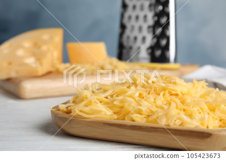 Delicious grated cheese on white wooden table, closeup Delicious grated cheese on white wooden table, closeup 105423673