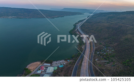 aerial view orange lights on the expressway along the route along the Lam Ta Khong Dam. beautiful scenery in the early morning wind mill on the mountains, rivers and sweet skies background. aerial view orange lights on the expressway along the route along the Lam Ta Khong Dam. beautiful scenery in the early morning wind mill on the mountains, rivers and sweet skies background. 105425105