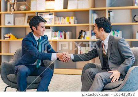 Executive men shaking hands in lobby Executive men shaking hands in lobby 105426058